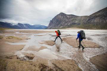 Two backpackers cross streams in Akshayak Pass, Baffin Island.