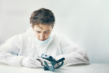 Man in white protective suit respirator mask on white background studio. Took off the mask after a...