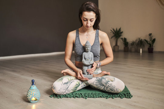 young woman meditates alone in yoga studio with aroma lamp and budda