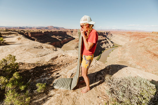 female camper blows up sleeping pad at a campsite above grand canyon