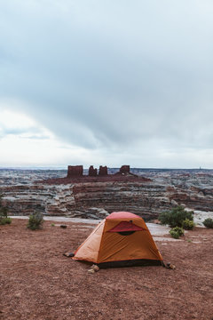 orange tent held down by rocks at campsite in The Maze Utah