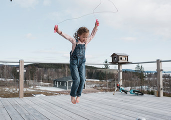 Girl playing with jump rope on balcony