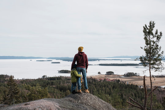 father and son standing on top of a hill together enjoying the view - Powered by Adobe