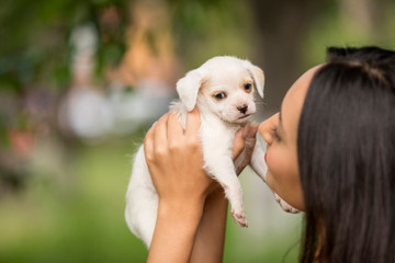 Woman with a small white puppy in her hands.