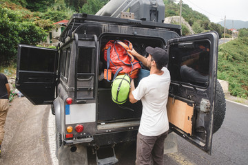 Mountain climber putting backpack into car trunk