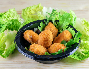 Assortment of croquettes of fish and meat, fresh green lettuce on the wooden kitchen table. Fast food concept.