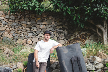 Pulled back portrait of make rock climber standing on crash pad