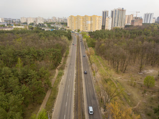 Street with tram tracks passing through the forest. Aerial view.