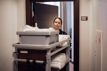 A hotel housekeeper pushing a cleaning supply cart