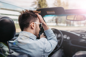 Fashionable male convertible driver rides on a sunny summer day.