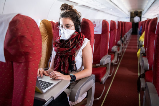 Young woman wearing a face mask while she works on an almost empty airplane due to the travel concerns and restrictions caused by the Covid-19 pandemic.