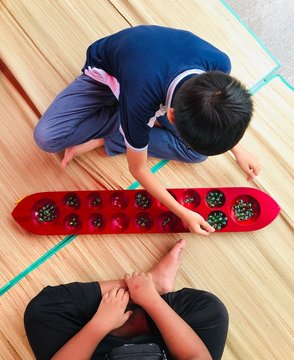 kids playing congkak (Malay traditional games)