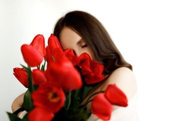 Portrait of a joyful girl holding a bouquet of red tulips isolated on a white background. Woman with tulips. Mother s day. Beautiful girl hugging a bouquet of tulips.