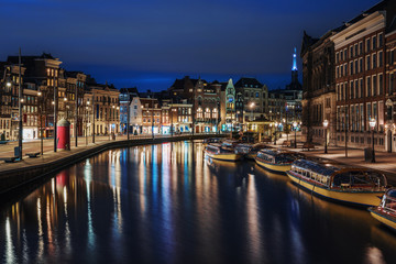 Amsterdam canal, Amstel river with city illumination reflection, Netherlands, Dutch city at night.