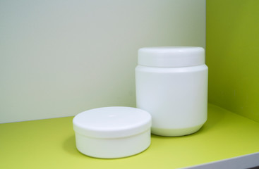 Jars of care products in white in various shapes and with different lids on a light background