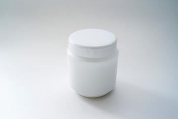 Jars of care products in white in various shapes and with different lids on a light background