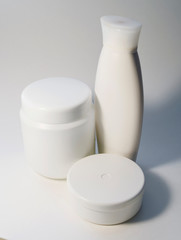 Jars of care products in white in various shapes and with different lids on a light background