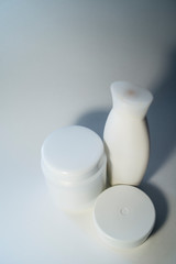 Jars of care products in white in various shapes and with different lids on a light background
