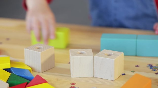 Online distance learning at home during quarantine. A smart child with glasses collects a multi-colored constructor at a table in a classroom.