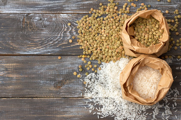 White rice basmati and green lentils in craft bags on a wooden background, rustic style, space, horizontal
