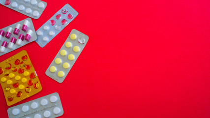 Close up of medical blister packs with tablets on red background. Packs with various tablets. Concept of threat of various diseases.