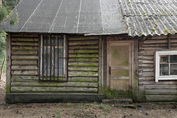 Fototapeta na wymiar An abandoned house or a barn in a forest with green and timbered log walls.