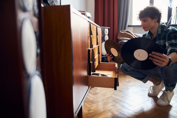 Attractive young man in shirt holding vinyl records