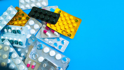 Close up of medical blister packs with tablets on blue background. Packs with various tablets. Concept of threat of various diseases.