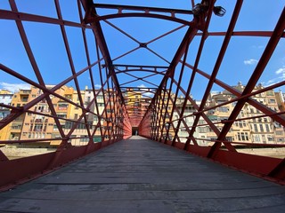 Nobody on red iron bridge in Girona, Catalonia, famous landmark under a blue sunny sky