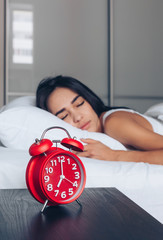 Alarm clock closeup and Young sleeping woman in bedroom