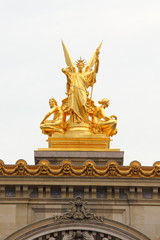 Fototapeta na wymiar One of the two golden statues on the roof of the Opera House, Palais Garnier in Paris, France