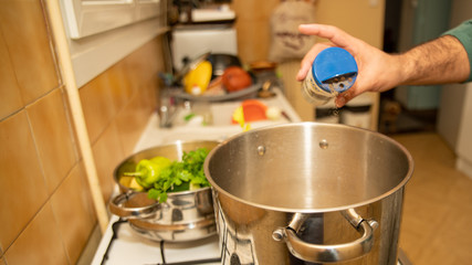 
Culinary preparation, a hand delivering pepper in a pot