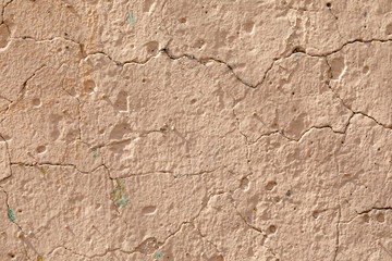 The texture of the concrete wall with irregularities, cracks, painted in sand color. Abstract background.