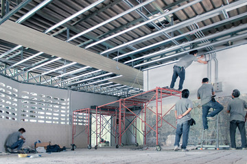 Ceiling technicians are installing electrical cables and insulation, ceilings inside the factory.