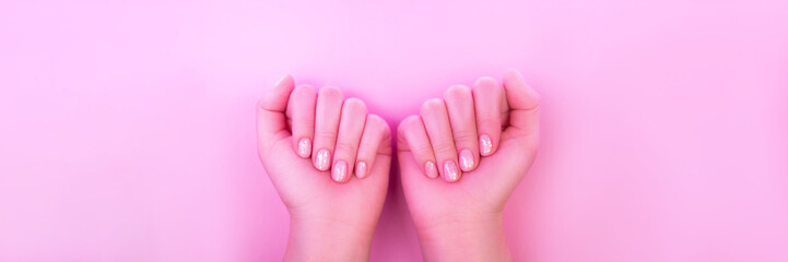 Female hands with perfect manicure in trendy neon light on pink background. Beauty concept.