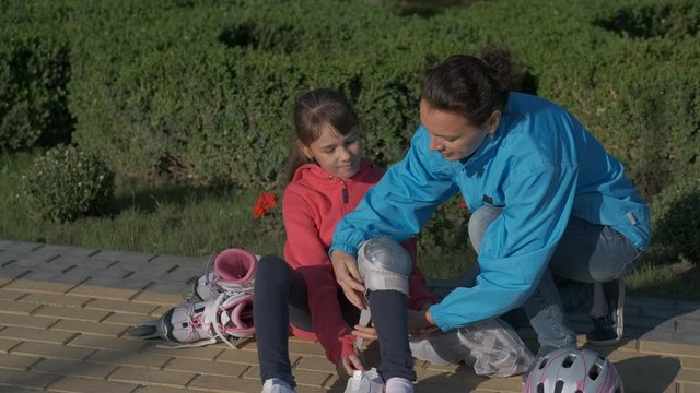 Protect for rollerskates. Daughter's mother puts on roller skating protection.