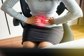 Woman having painful stomach ache during working from home,Female suffering from abdominal...