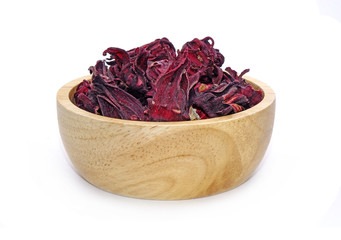 Dried Roselle flower buds in wooden bowl isolated on white background. In Traditional Chinese Medicine, roselle flower buds are in Herbs that relieve coughing and wheezing category. Rosella