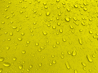 Drops of water on a yellow metal surface, beautiful background after rain