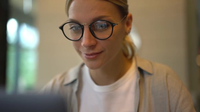 Millennial female in glasses making online shopping during Cyber Monday checking cvc code information on plastic credit card for writing during money transaction for order delivery in web store
