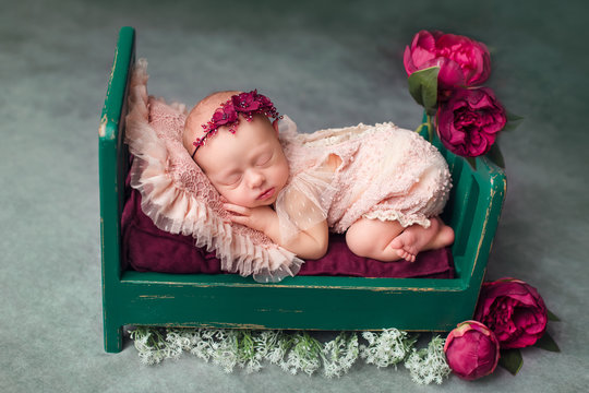 a newborn baby a little girl is lying in a crib. bed decor with red peonies. first photo session