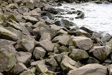 Rocky riverbank. Waves rise against rocks.