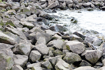 Rocky riverbank. Waves rise against rocks.