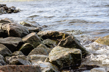 Rocky riverbank. Waves rise against rocks.