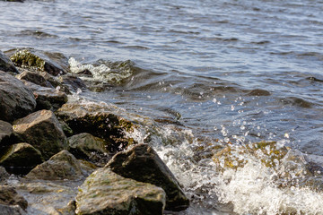 Rocky riverbank. Waves rise against rocks.