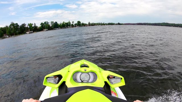 Point of view (POV) GoPro shot of man on a jetski watercraft riding on a lake on a sunny day, enjoying fun summer excitement on the water.