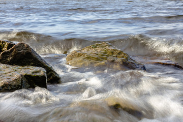 Rocky riverbank. Waves rise against rocks.