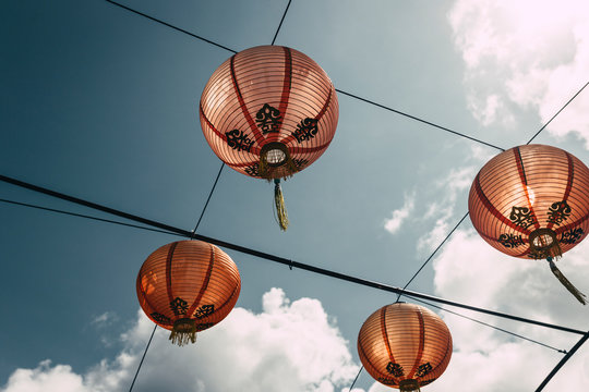Low Angle View Of Chinese Lanterns Hanging On Cable Against Sky