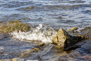 Rocky riverbank. Waves rise against rocks.