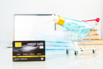 Credit card in shopping cart front of laptop screen with alcohol gel bottle , Work from home concept
